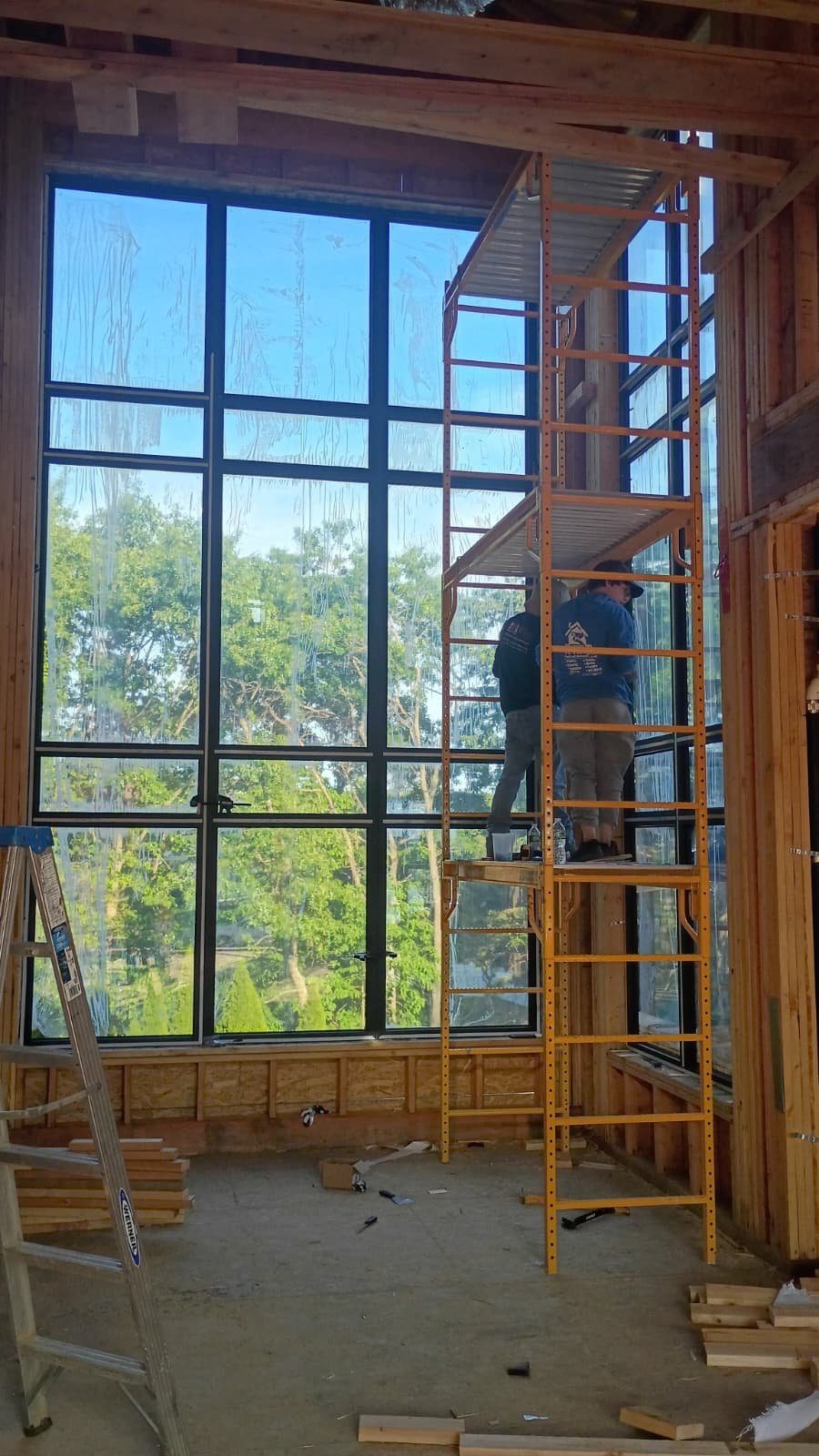 Corner room with a black-framed window wall on one side and a multi-panel sliding door system on the other