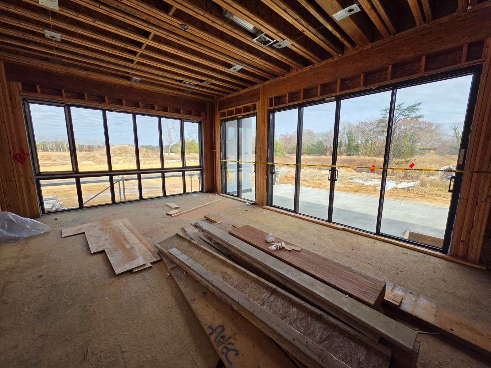 Double-height room with four tall divided-lite black windows during framing