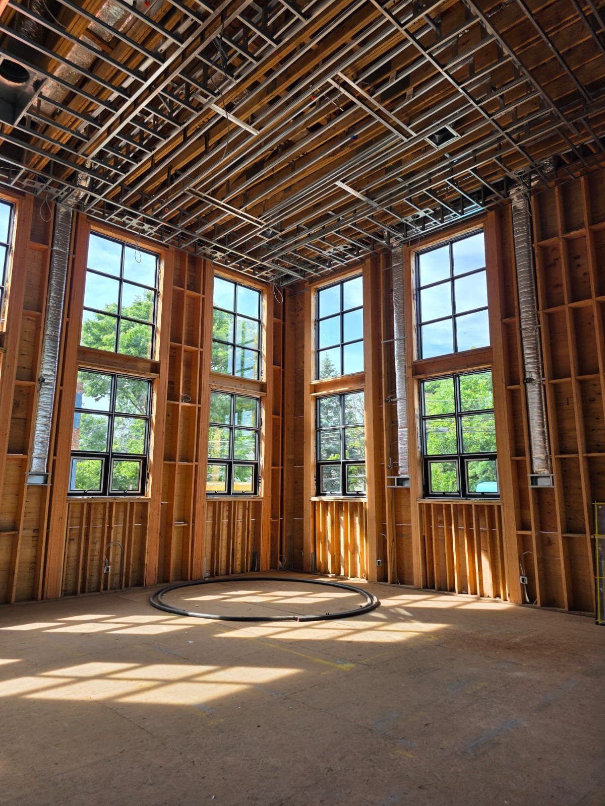 Installers on scaffolding fitting a tall black-framed grid window wall during construction